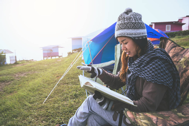 アジアの女性は休日にリラックス旅行します。山でキャンプをする。椅子の上に本を読んで座るタイ - 写真・画像