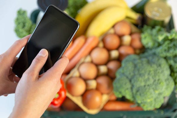 Essenslieferdienst - Frau hält Smartphone vor die Tür - Foto, Bild