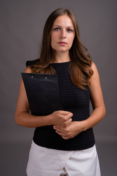 Studioaufnahme einer jungen schönen Geschäftsfrau vor grauem Hintergrund - Foto, Bild