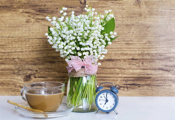 Bouquet of Lily of the Valley with Alarm Clock and Cup of Coffee on  Wooden Background .Spring Morning Concept - Fotografie, Obrázek