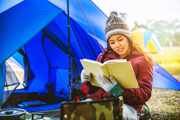 アジアの女性は休日にリラックス旅行します。山でキャンプをする。椅子にメモを書いてください。山の観光一晩キャンプ。キャンプテント、キャンプタイ、教育、本、本、日記を読みます。旅行タイ. - 写真・画像