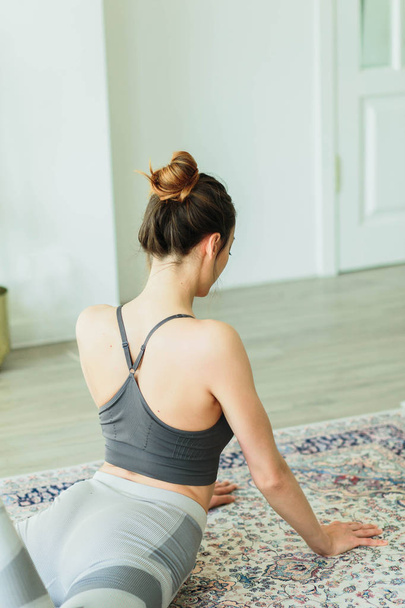 Giovane donna attraente sorridente che pratica yoga in una stanza luminosa
 - Foto, immagini