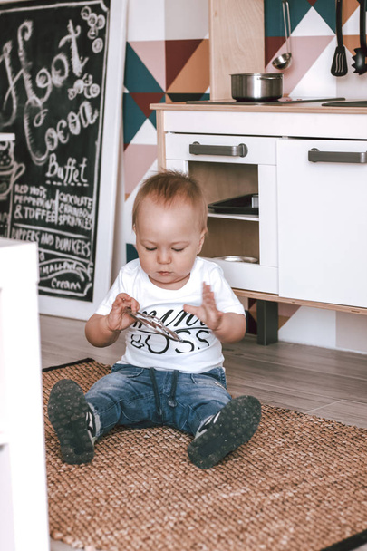 Happy baby boy small playing with toys in kids room in jeans and white t-shirt - Фото, зображення