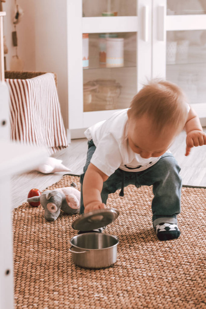 Happy baby boy small playing with toys in kids room in jeans and white t-shirt - Foto, Bild