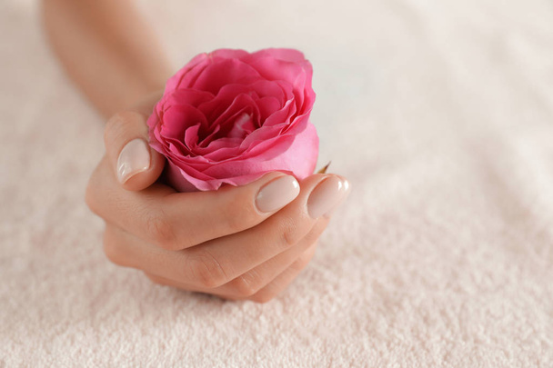 Close-upweergave van de vrouw met gladde hand en bloem op handdoek, ruimte voor tekst. Spabehandeling - Foto, afbeelding