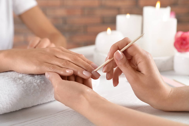 Manicurist working with client's nails at table, closeup. Spa treatment - 写真・画像