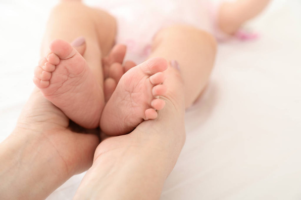 Mother holding her baby's feet on bed, closeup - Photo, Image