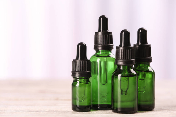 Bottles of essential oils on table against light background, space for text. Cosmetic products - 写真・画像