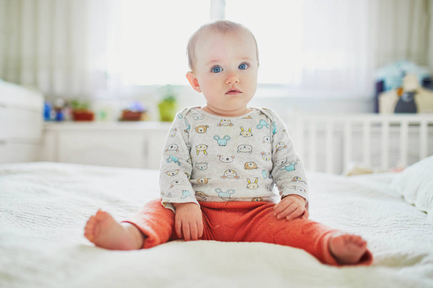 Baby girl sitting on bed. - Fotó, kép