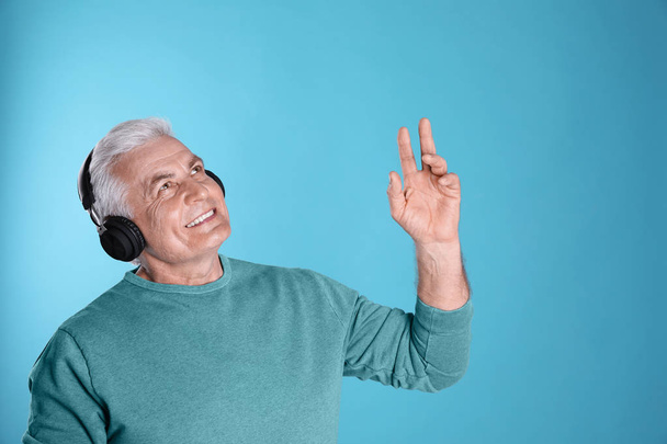 Mature man enjoying music in headphones on color background. Space for text - Foto, immagini