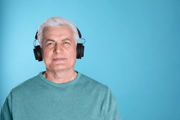 Dojrzały człowiek ciesząc się muzyką w słuchawkach na kolorowym tle. Miejsce na tekst - Zdjęcie, obraz