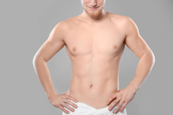 Young man with slim body in towel on grey background, closeup - Zdjęcie, obraz