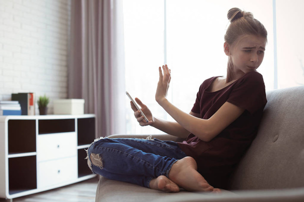 Terrified teenage girl with smartphone in room. Danger of internet - Foto, Bild