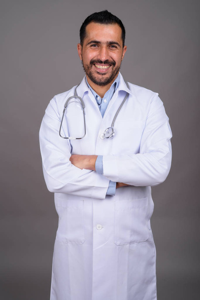 Yakışıklı sakallı İranlı doktorun gri arka planda çekilmiş bir fotoğrafı. - Fotoğraf, Görsel
