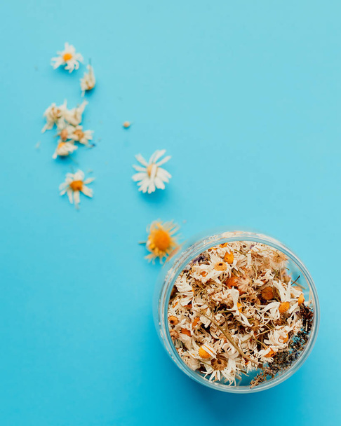 dried chamomile in a jar on a blue background. - Photo, Image