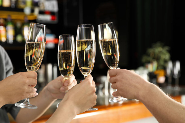 Friends clinking with glasses of champagne in bar, closeup - Fotoğraf, Görsel
