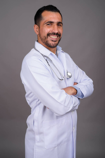 Studio záběr pohledný vousatý perský muž lékař na šedém pozadí - Fotografie, Obrázek