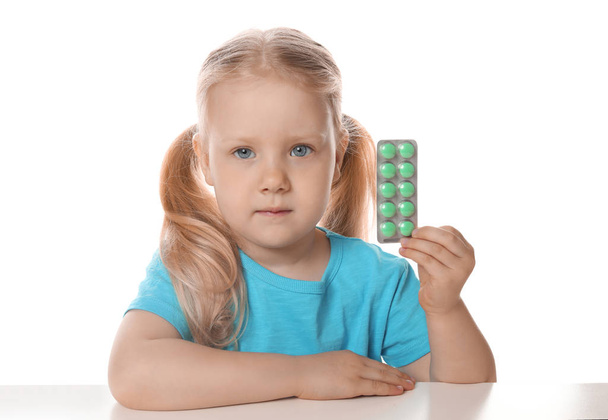 Little child with pills on white background. Danger of medicament intoxication - Photo, image