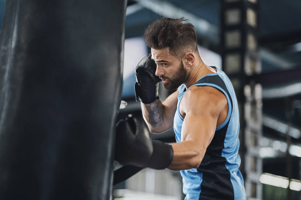 Aktywny facet wykrawania torba bokserska na siłowni - Zdjęcie, obraz