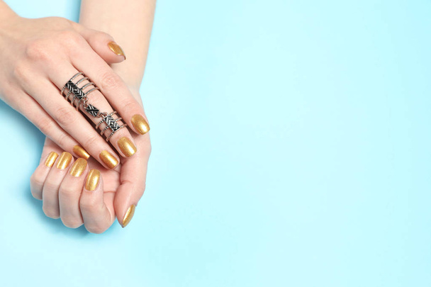 Woman showing manicured hands with golden nail polish on color background, top view. Space for text - 写真・画像