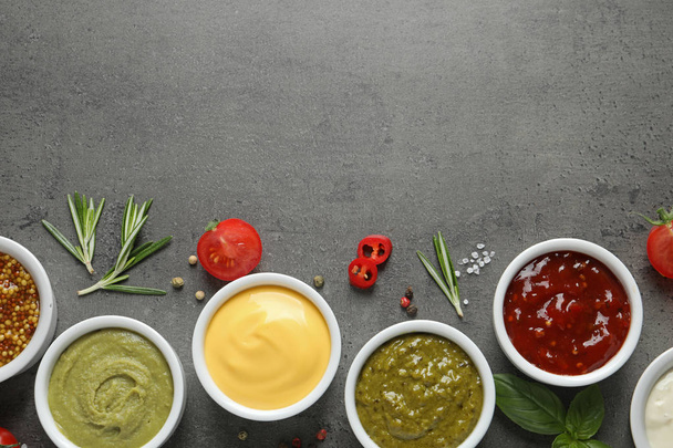 Bowls with different sauces and ingredients on gray background, flat lay. Space for text - Foto, Imagem