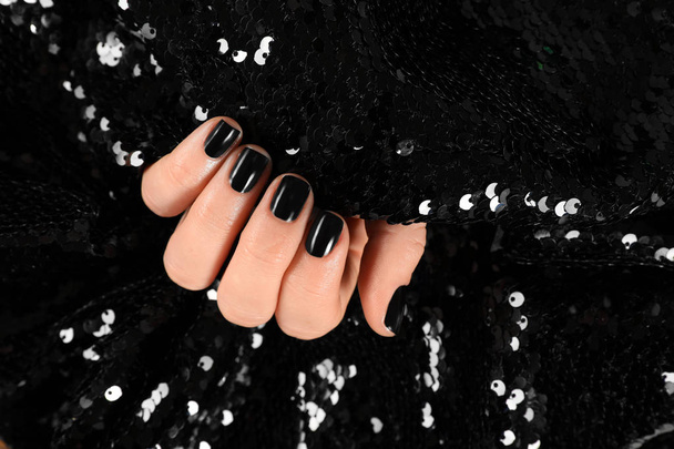 Woman with black manicure holding shiny fabric, closeup. Nail polish trends - Foto, Imagen