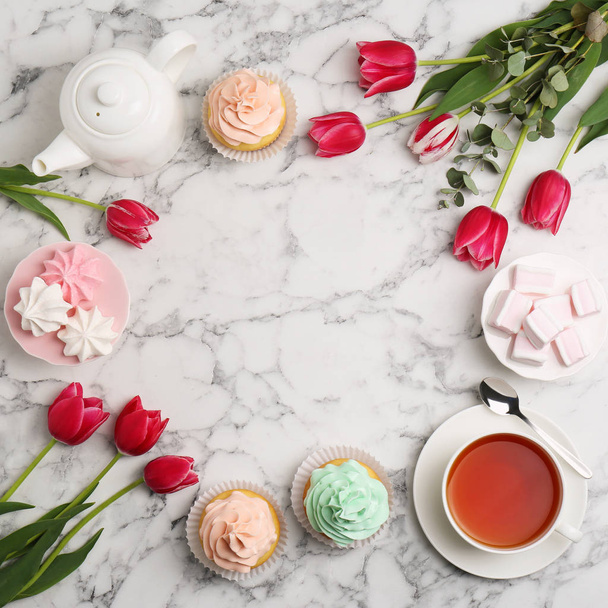 Beautiful composition with tea, desserts and tulips on marble background, flat lay. Space for text - Foto, afbeelding