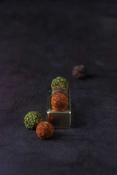 chocolate round candies sprinkled with spices on a dark background - Фото, зображення