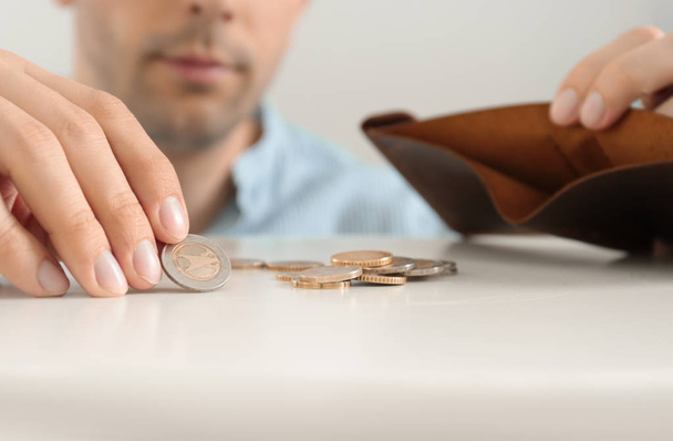 Man putting coins in wallet at table, closeup - Fotó, kép