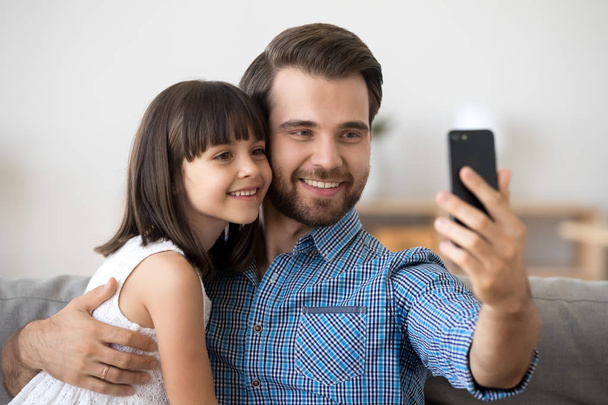Smiling young dad and little daughter making selfie on smartphone - Fotoğraf, Görsel