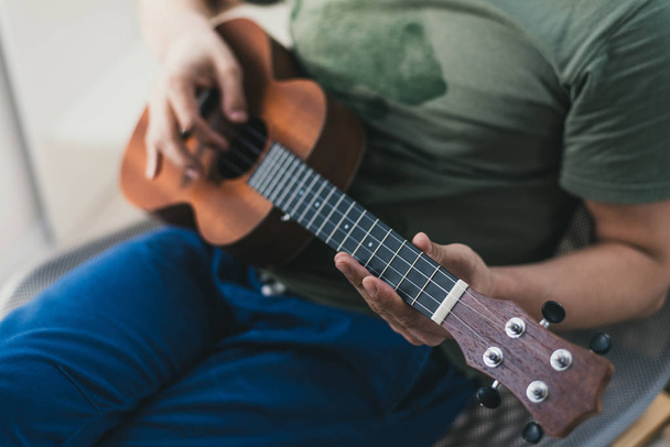 ukulele oyunu. Biraz gitar çalan bir adam. sanatçı evde ukulele müzik yazar. - Fotoğraf, Görsel