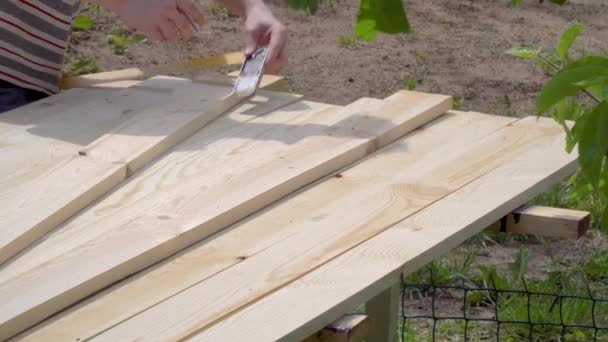 Close-up van een man markeert geschafte houten planken met een potlood en meetlint - Video