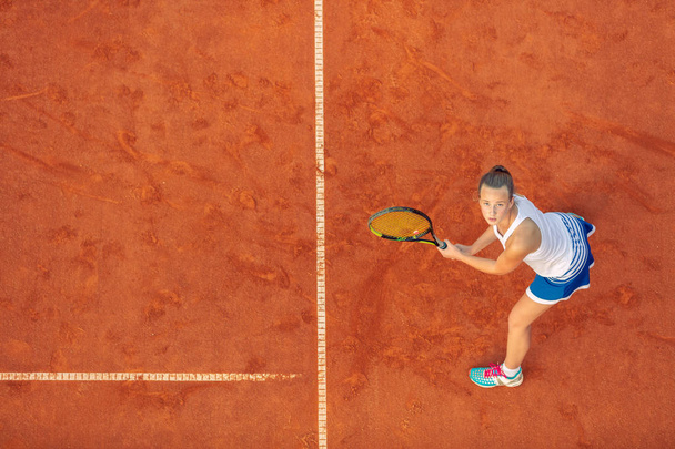 Aerial shot of a female tennis player on a court during match. Young woman playing tennis.High angle view. - 写真・画像
