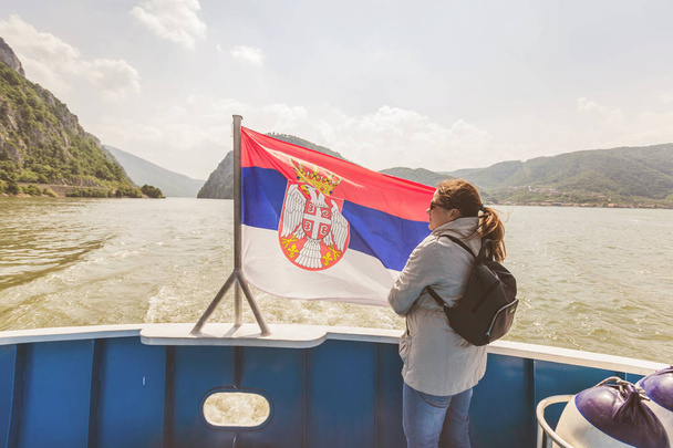Donna in crociera sul fiume con bandiera nazionale serba godere della vista della gola del Danubio
  - Foto, immagini