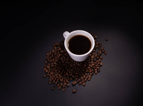Coffee beans and a cup of coffee in soft top lighting - Photo, image