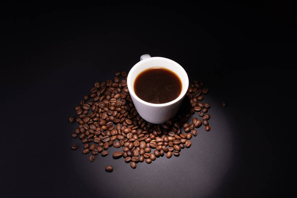 Coffee grains among which there is a cup illuminated by a limite - Foto, Imagem