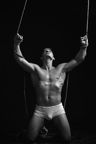 Sexy macho man do gymnastic. Man with muscular body on rope. Circus gymnast at pilates or yoga training. Sport workout for bodybuilder. Fitness dieting and flexibility in acrobatics. - Foto, immagini