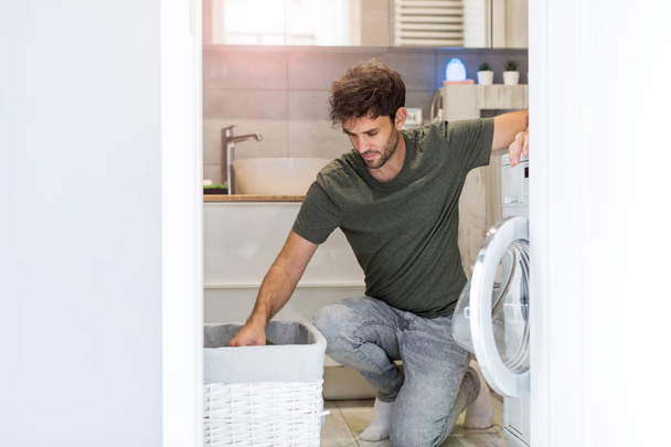 Man Putting his Laundry into a Washing Machine - Photo, Image