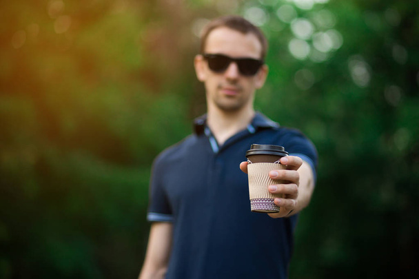 J'aime le café frais. Beau jeune homme en tenue décontractée tenant tasse jetable et souriant tout en marchant dans la rue de la ville
 - Photo, image