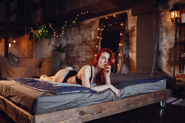 Je me repose. Portrait d'une fille rousse sexy sur le sol posant dans la chambre en bois
. - Photo, image