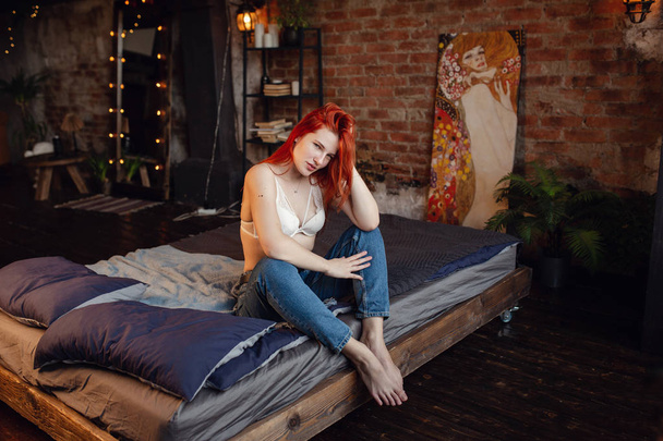 Αναπαύσου. Πορτραίτο ενός σέξι κοκκινομάλλα κορίτσι στο πάτωμα που ποζάρει στο ξύλινο δωμάτιο. - Φωτογραφία, εικόνα