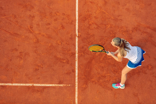 Aerial shot of a female tennis player on a court during match. Young woman playing tennis.High angle view. - Foto, Imagen