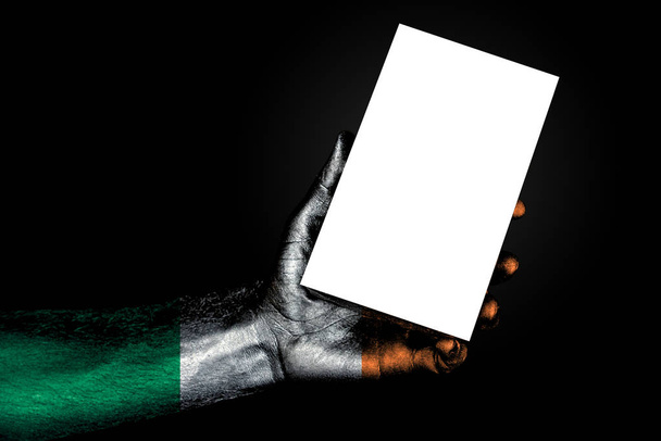 hand with painted flag Ireland holding a large white sheet with space for an inscription, mock up - Photo, Image