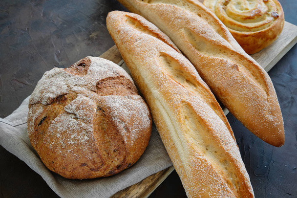 Baguettes fraîchement cuites, pain et pain sur une serviette de lin
. - Photo, image