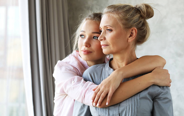 lifestyle and people concept - beautiful senior mom and her adult daughter are hugging, looking at camera and smiling. - Valokuva, kuva