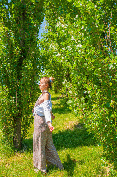 Beautiful boho style woman in fashionable jumpsuit enjoying summer time in park - Fotoğraf, Görsel