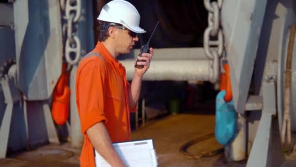 Zeevaartkundig scheepsofficier op het dek van offshore vaartuig bezit walkie-talkie marifoon - Video