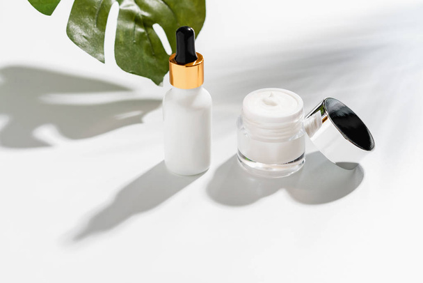 White serum bottle and cream jar, mockup of beauty product brand. Top view on the white background. - Foto, Imagem