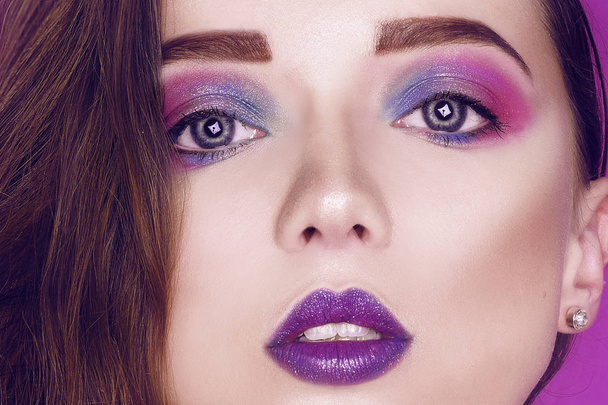 Fashion model woman creative pink and blue make up.  Beauty art portrait of beautiful girl with colorful abstract makeup. Beautiful Eyes Glitter . Purple bright lips, long cerly hair. Pink background - Photo, Image