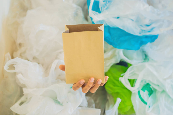 Kağıt torba plastik torba yığını arasında. Sıfır atık kavramı. Dünya Çevre Günü kavramı - Fotoğraf, Görsel